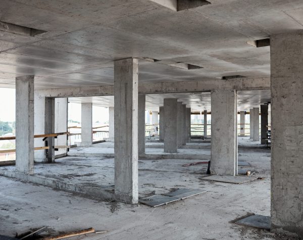 Background image of unfinished building at construction site with concrete columns, copy space